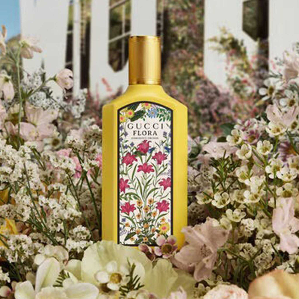 Gucci Flora Gorgeous Orchid Eau de Parfum 100ml displayed among lush garden flowers, emphasizing its luxurious floral scent.